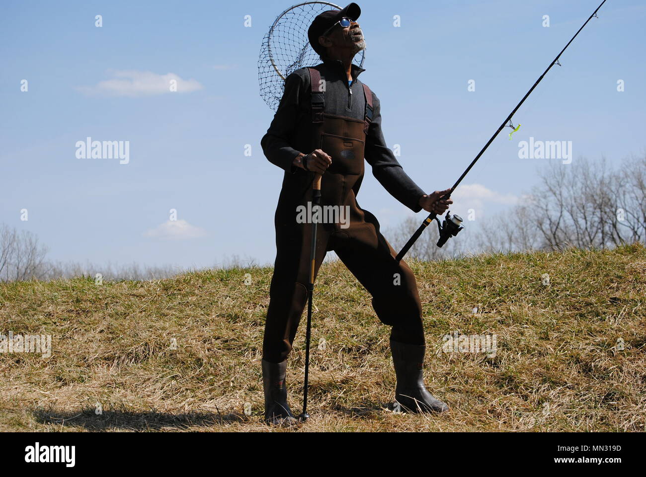 WALLEYE HUNTER, STYLES, CHEST WADER BOOTS,STICK, NET, AND TACKLE BAG. Stock Photo
