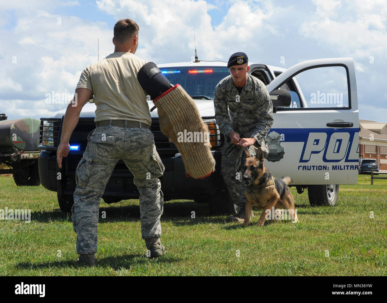 (Left) U.S. Air Force Staff Sgt. Jeffrie Kennedy, 633rd Security Forces Squadron military working dog handler, readies his partner, Toni, 633rd SFS MWD, to attack at Joint Base Langley-Eustis, Va., Aug. 4, 2017. To maintain readiness, Kennedy and Toni practice base defense techniques every day. (U.S. Air Force photo/Airman 1st Class Anthony Nin Leclerec) Stock Photo