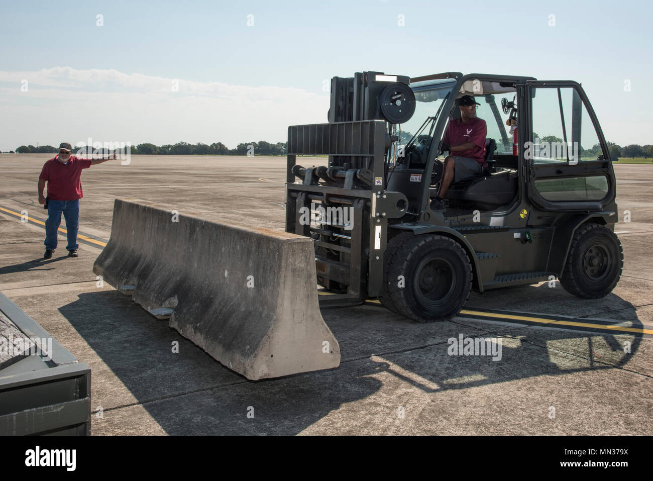 (Left to right) Jaime Gomez, 12th Operations Support Squadron assistant airfield manager, and Mathew Calendar, 502nd Logistics Readiness Squadron forklift operator, place concrete barriers on the flightline at Joint Base San Antonio-Randolph, Texas Aug. 30, 2017. Concrete barriers were placed along the flightline to create a staging area for trailer trucks containing supplies to aid in Hurricane Harvey disaster relief efforts.  (U.S. Air Force photo by Senior Airman Stormy Archer) Stock Photo