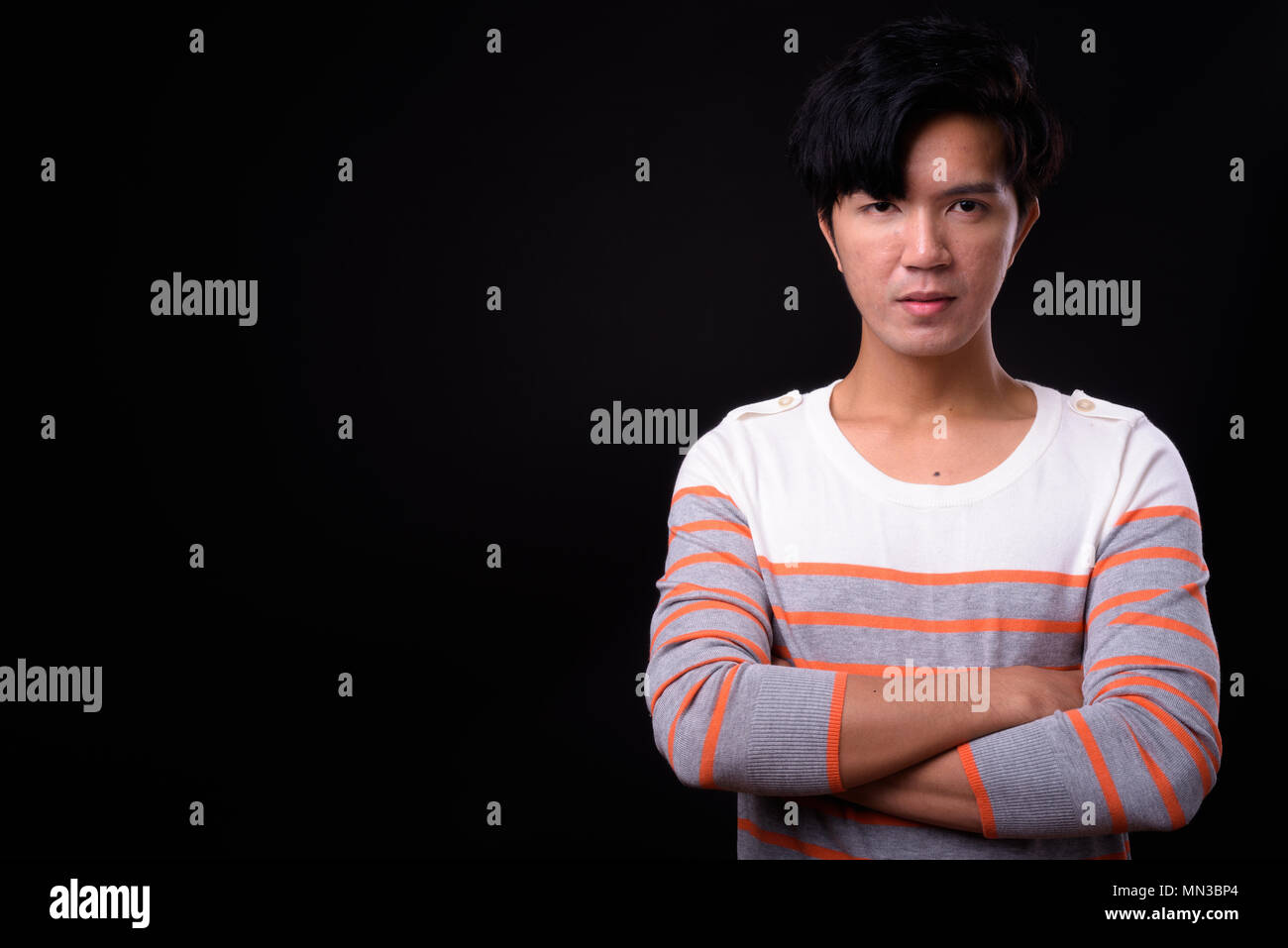 Young handsome Asian man against black background Stock Photo
