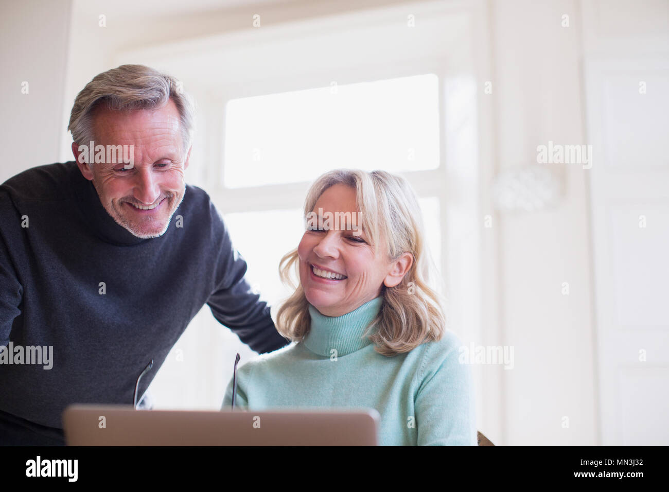 Smiling mature couple using laptop Stock Photo