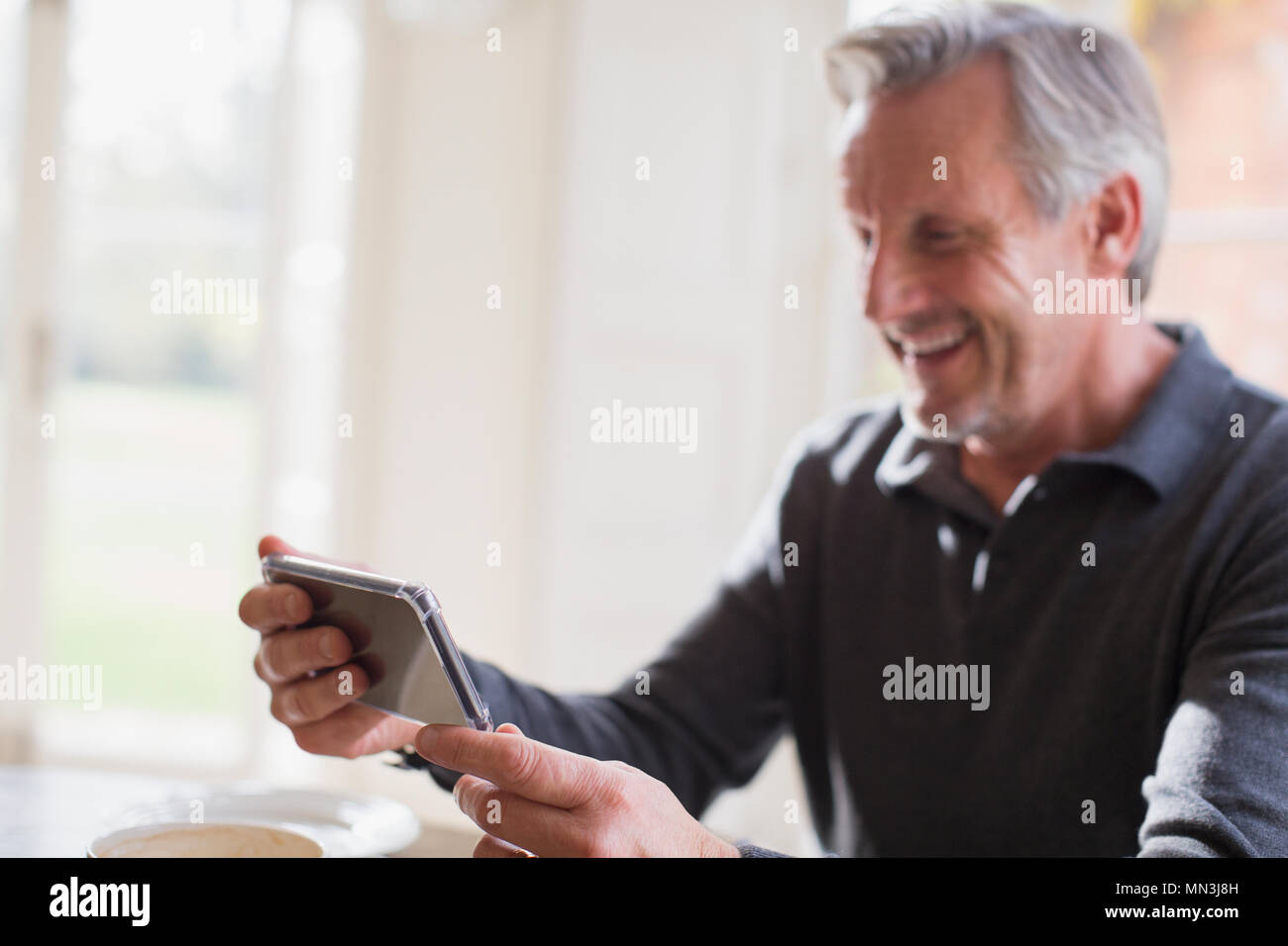 Smiling mature man using smart phone Stock Photo