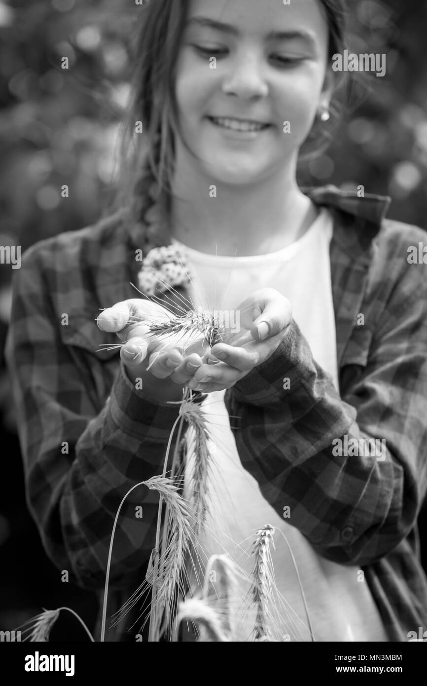 Black and white closeup image of smiling teenage girl holding ripe white in hands Stock Photo