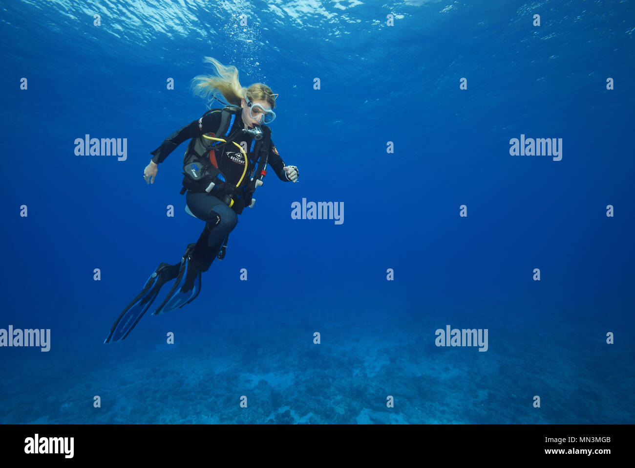 Female scuba diver run in the blue water underwater, is having fun in time safety stop in a strong current Stock Photo