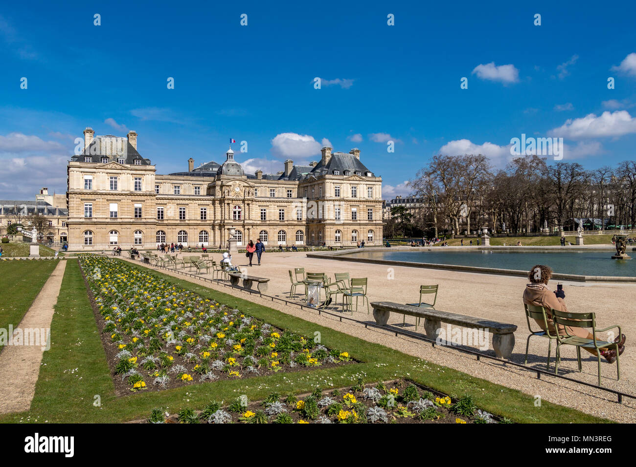 People sitting in the winter sunshine by the octagonal pool of water in the Jardin du Luxembourg ,Paris ,France Stock Photo