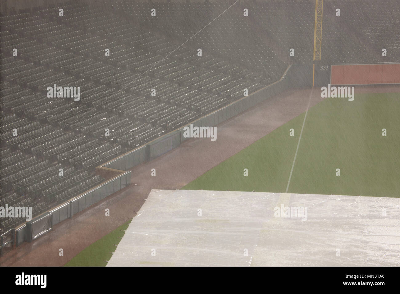 Empty seats in baseball stadium stands during thunderstorm delay with