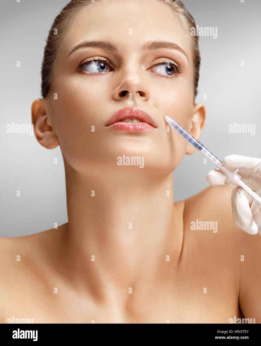 Beautiful woman face and beautician hands with syringe making rejuvenate injection. Clean Beauty concept Stock Photo