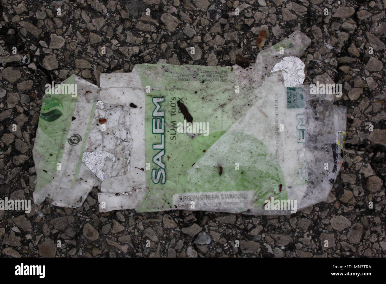 Smushed and flattened empty pack of Salem cigarettes found on the ground in a parking lot. Stock Photo