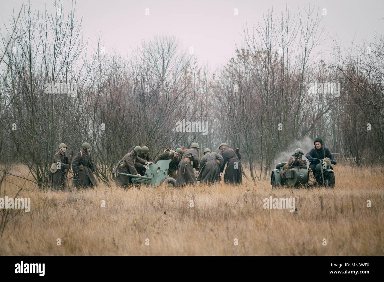 Gomel, Belarus - November 26, 2017: Soldiers of the Red Army deploy a cannon for battle in the autumn field. Reconstruction of the battle for the libe Stock Photo