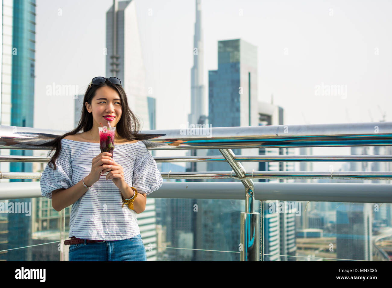 Girl having a drink with Dubai city view Stock Photo