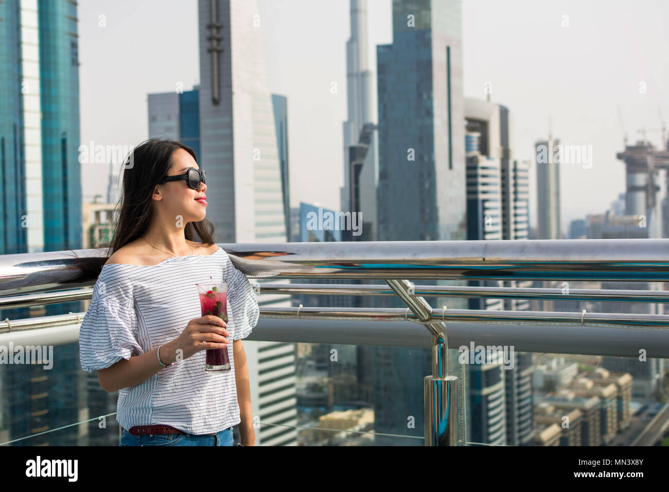 Girl having a drink with Dubai city view Stock Photo