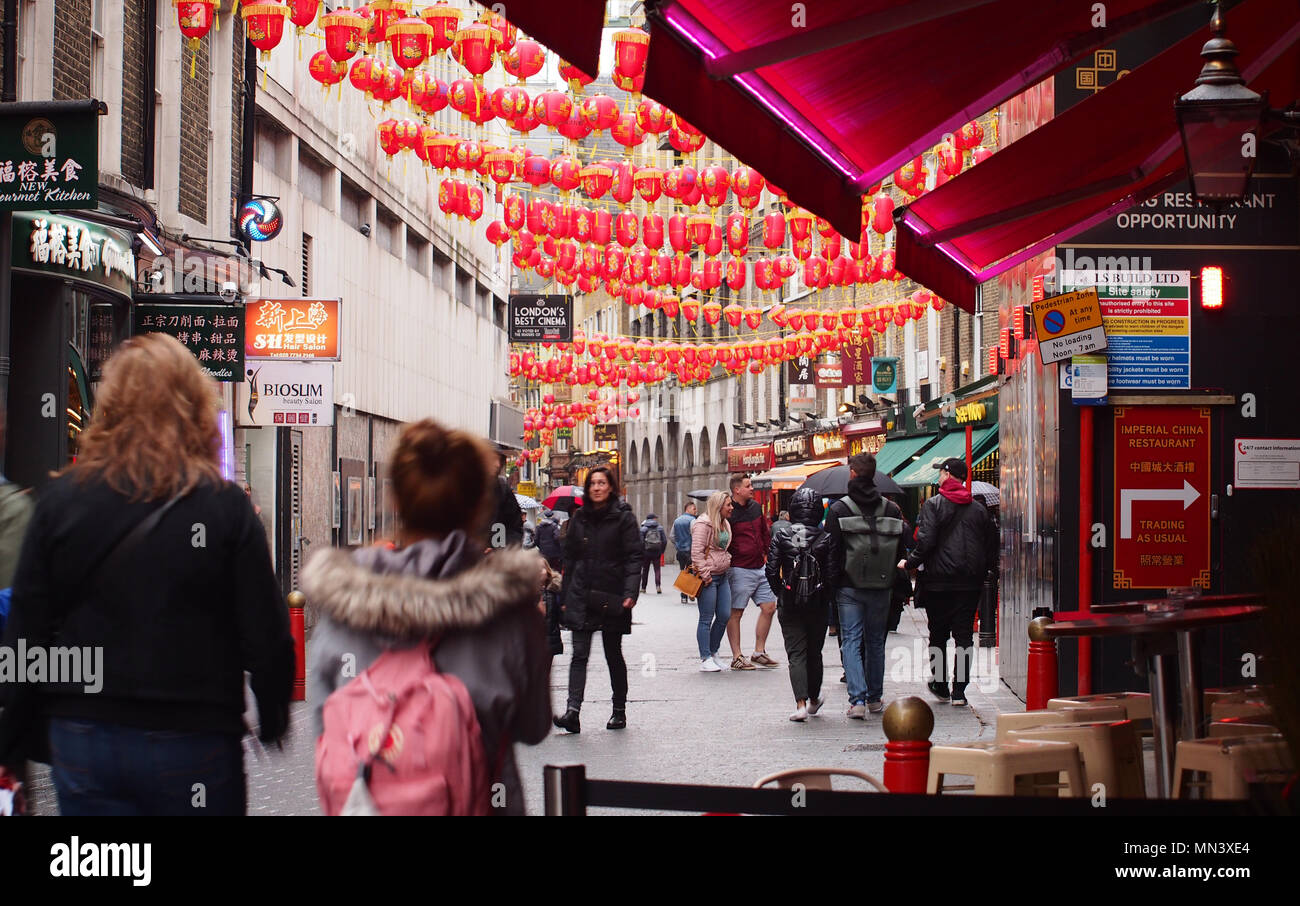 Pedestrians, sightseers and visitors walking under Chinese lanterns in China Town, London Stock Photo