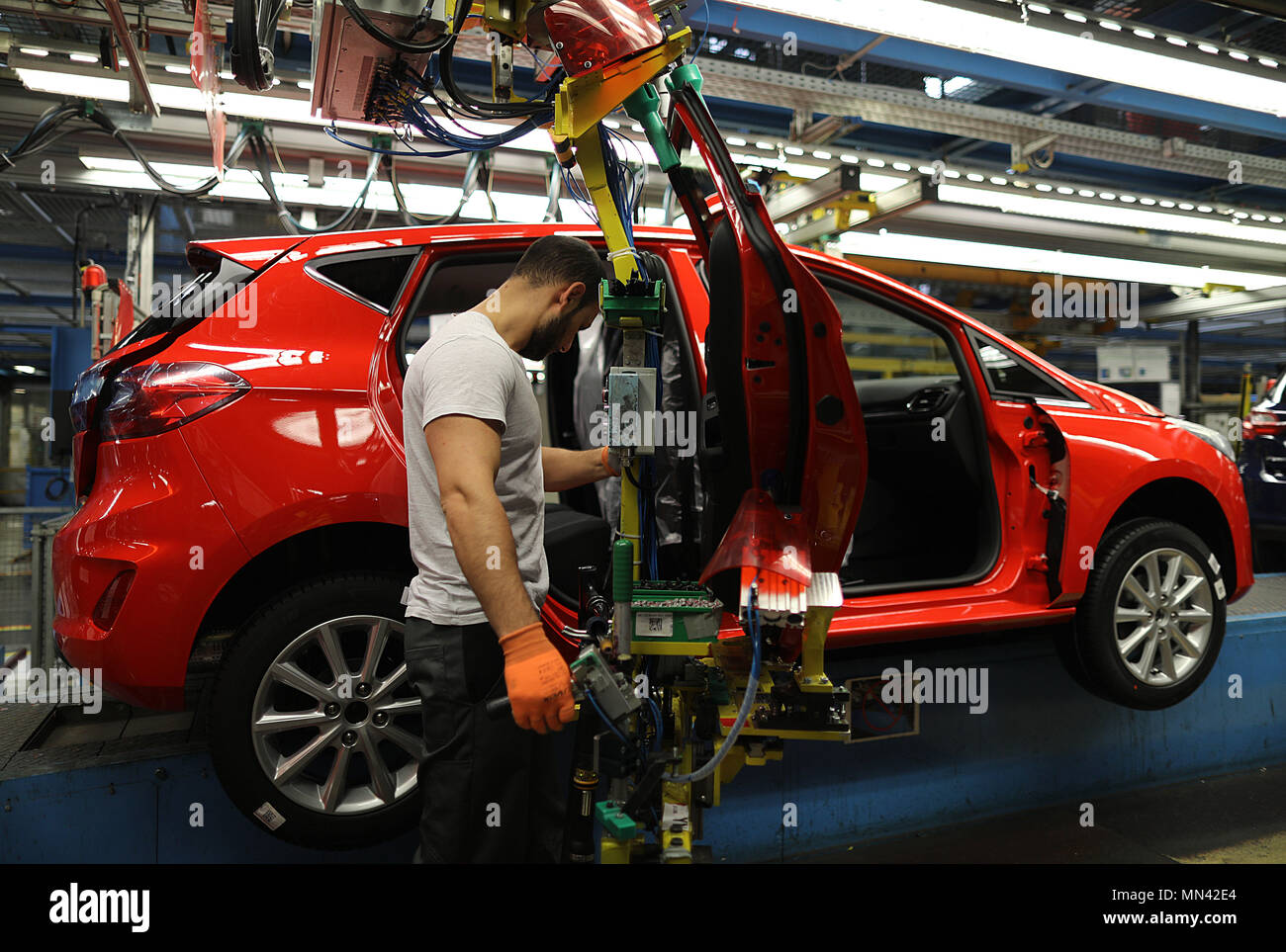 09 May 2018, Germany, Cologne: A Ford employee mounts a door of a Ford Fiesta on the conveyor belt. Photo: Oliver Berg/dpa Stock Photo