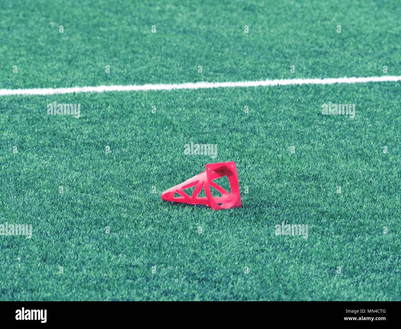 Bright red plastic cone on soccer field. Plastic football green turf