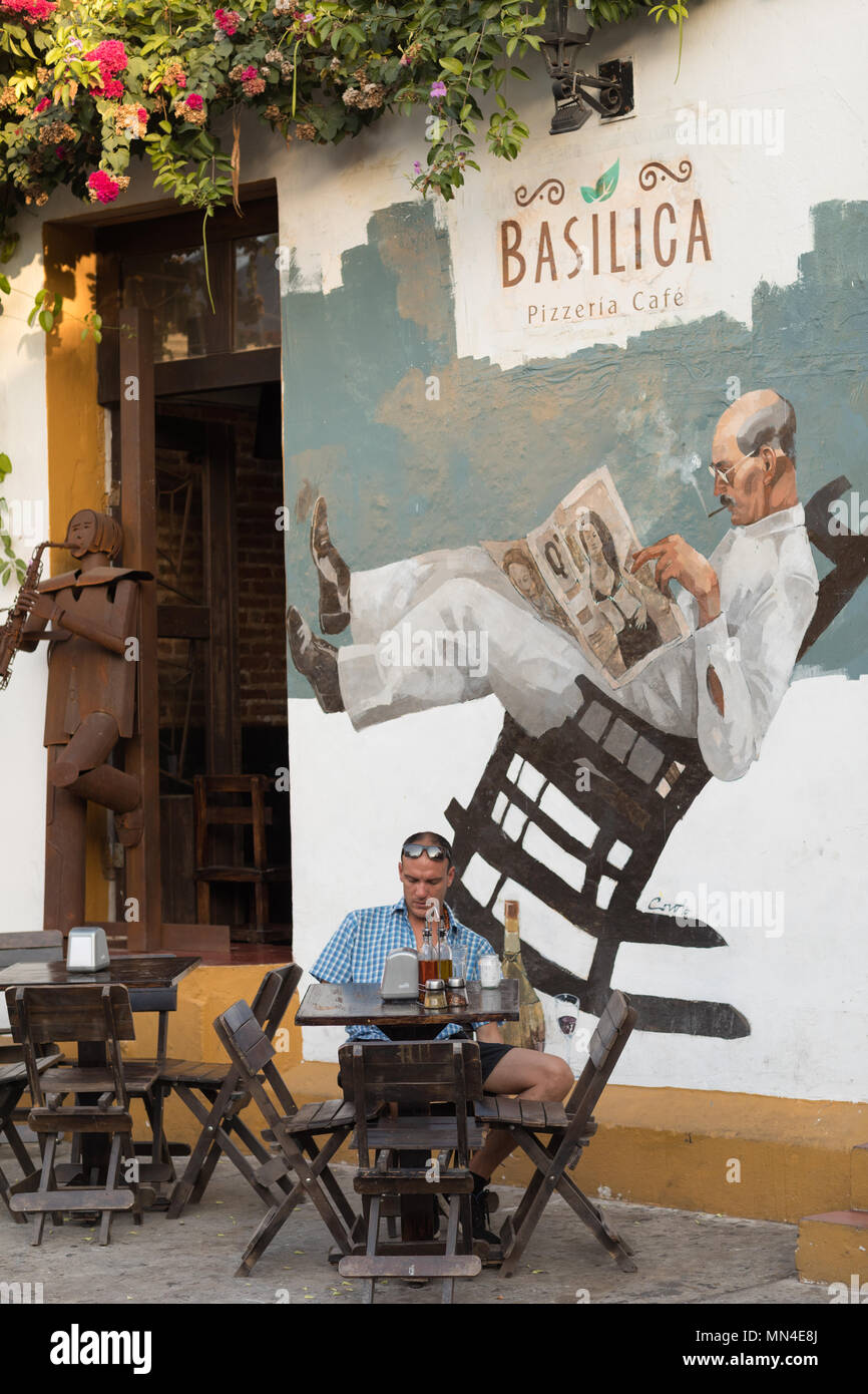 A man outside a cafe on the colourful streets of Getsemani, Cartagena, Colombia Stock Photo