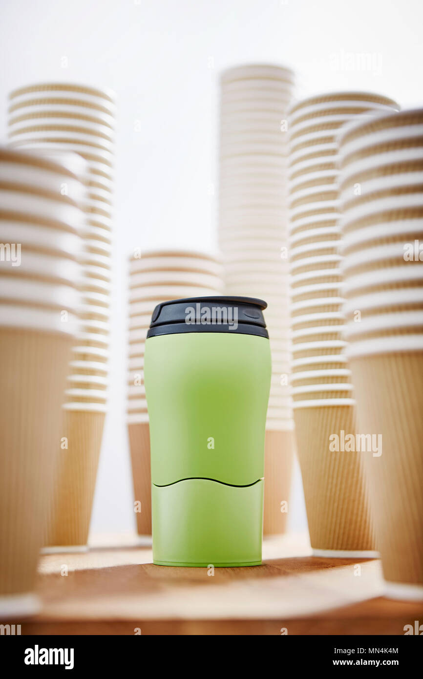 Green insulated drink container surrounded by disposable coffee cups Stock Photo