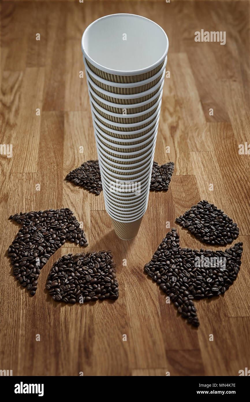 Coffee beans forming recycle symbol around stack of recyclable coffee