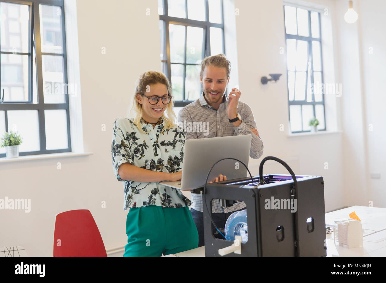 Designers using laptop at 3D printer in office Stock Photo