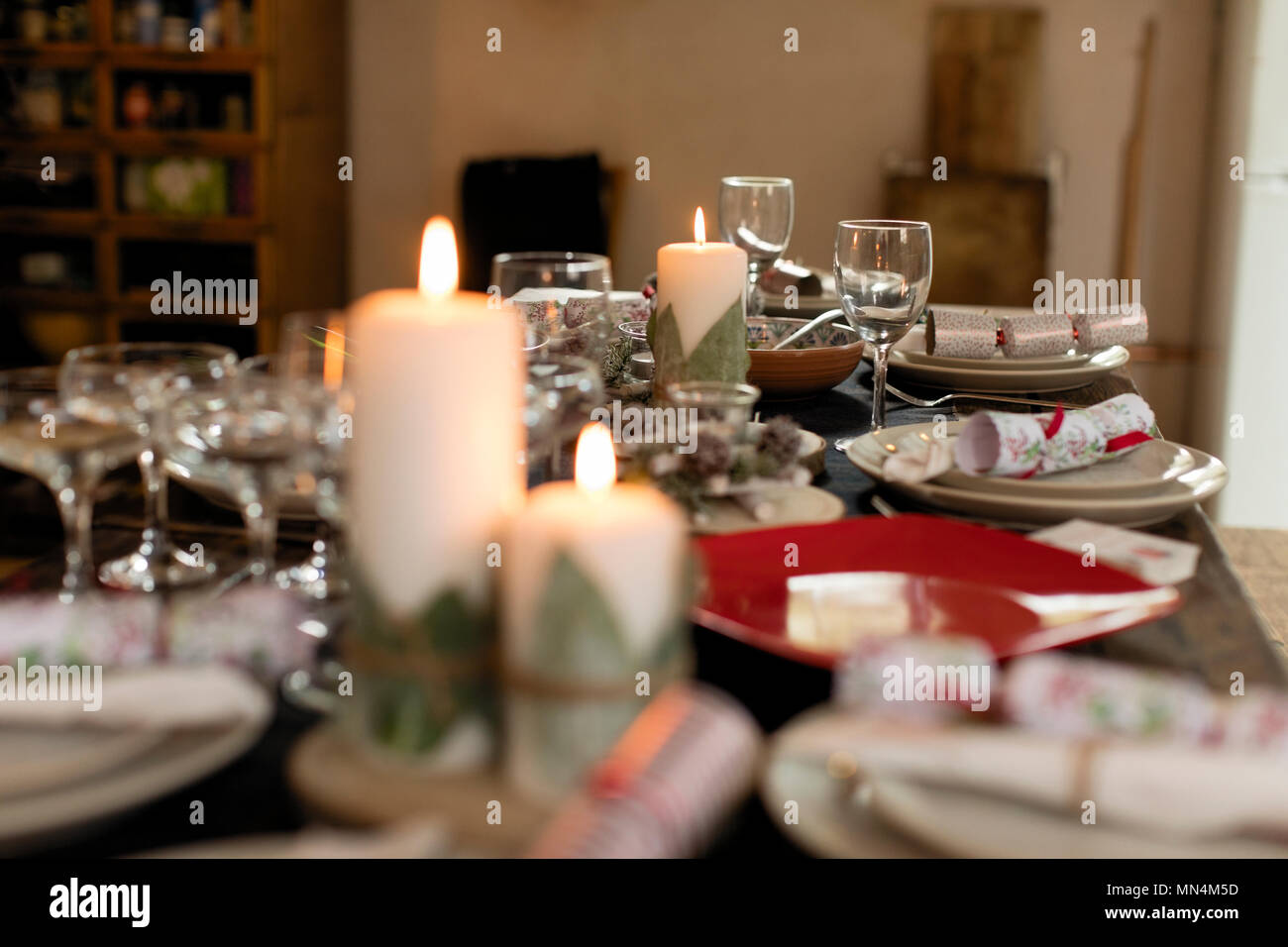 Candles, placesettings and Christmas crackers on table Stock Photo