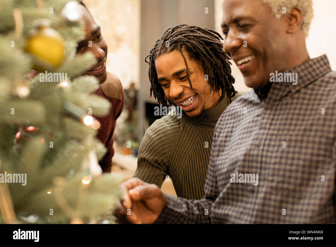 Smiling grandfather and grandsons decorating Christmas tree Stock Photo