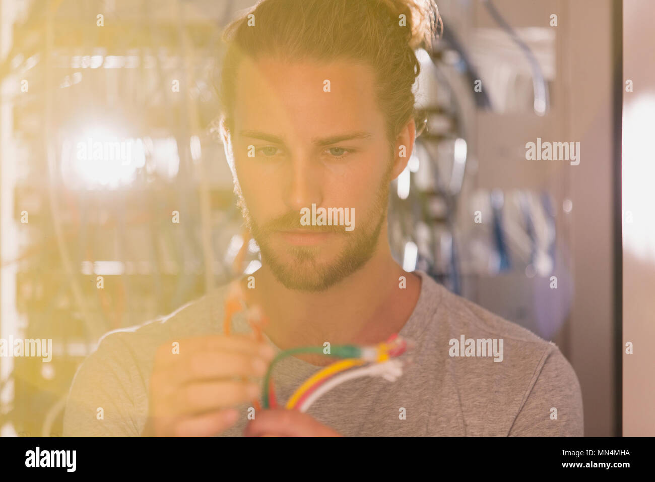 Focused IT technician examining connection plugs in server room Stock Photo
