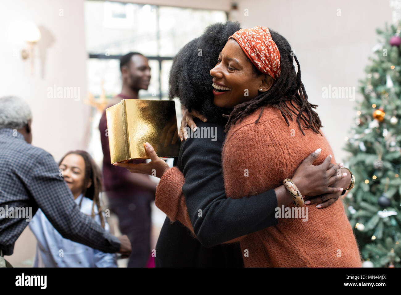 Happy mother and daughter with Christmas gift hugging Stock Photo
