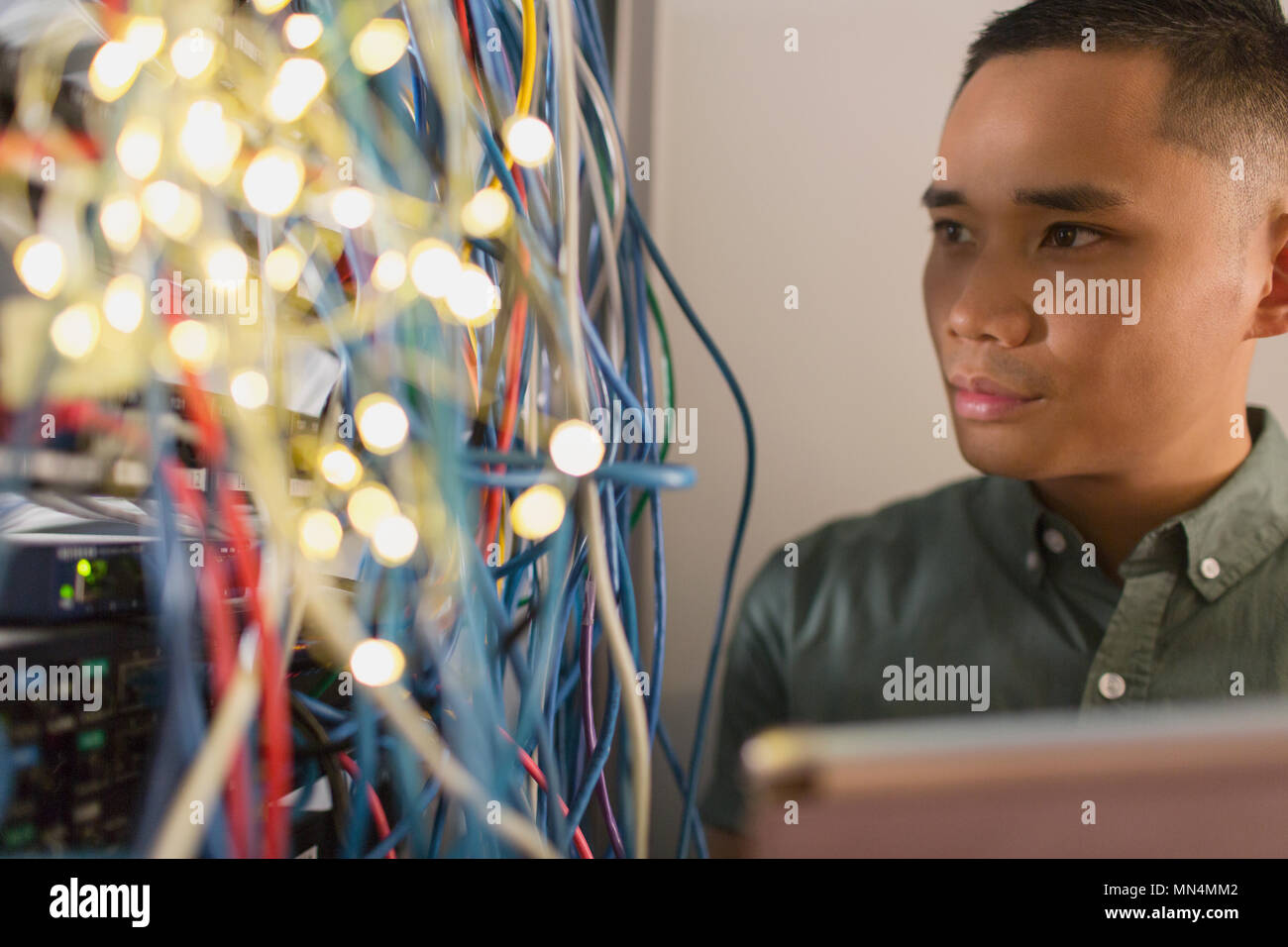 Focused male IT technician examining wires on server panel Stock Photo