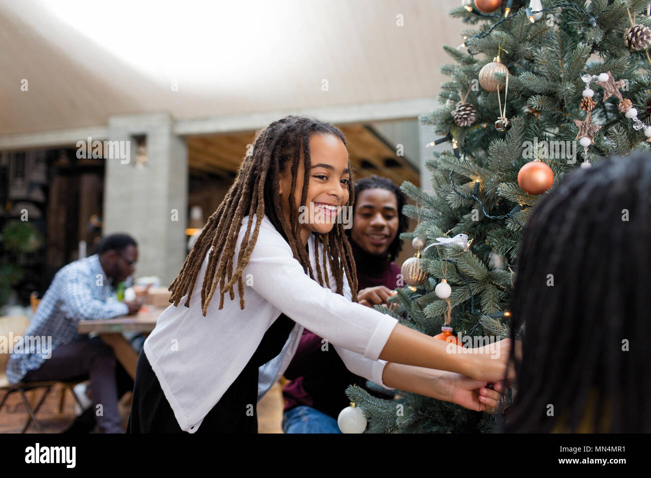 Happy girl decorating Christmas tree with family Stock Photo
