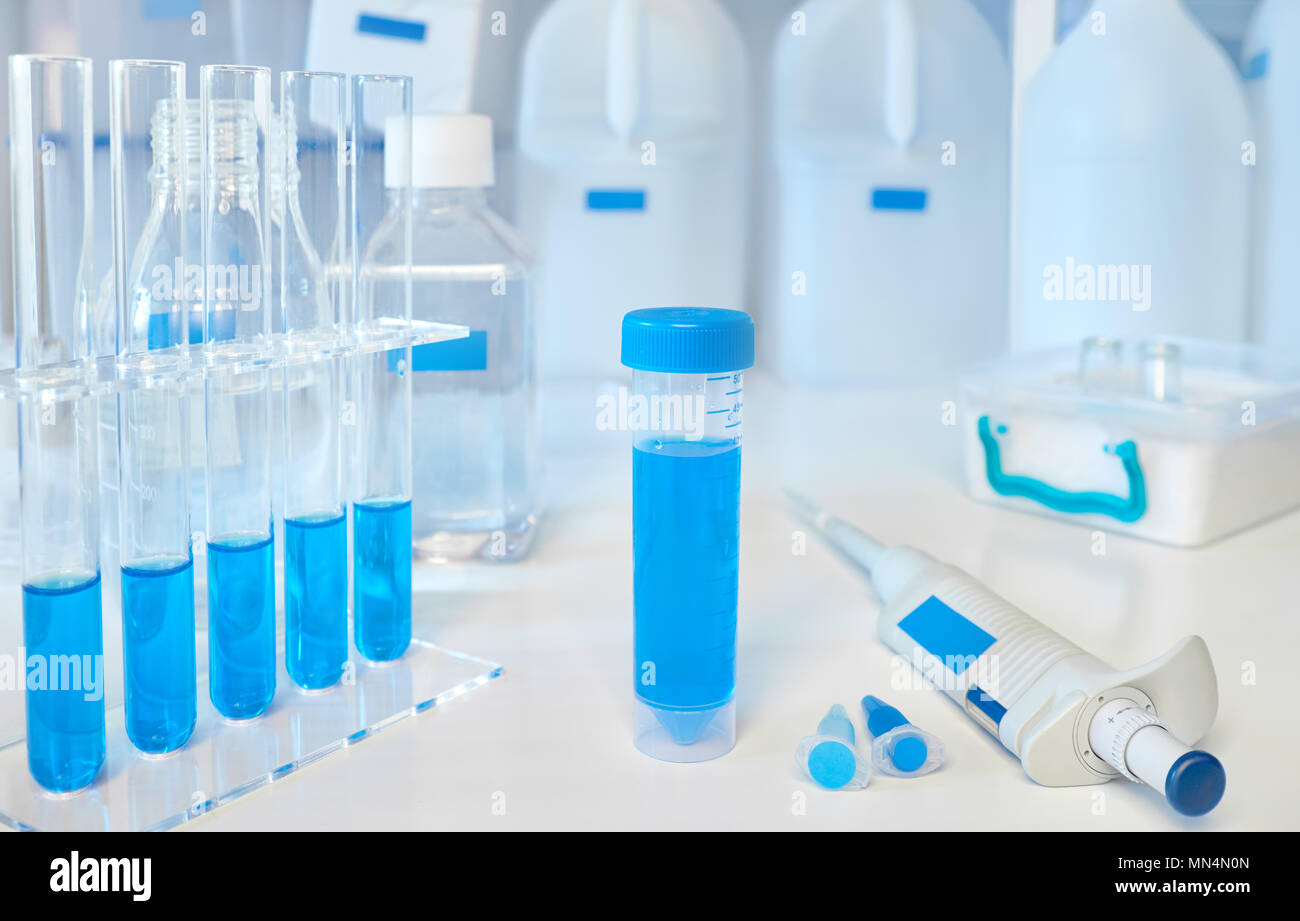 Scientific background in blue and white. Liquid samples in glass and plastic tubes, automatic pipette and ice basket. Stock Photo