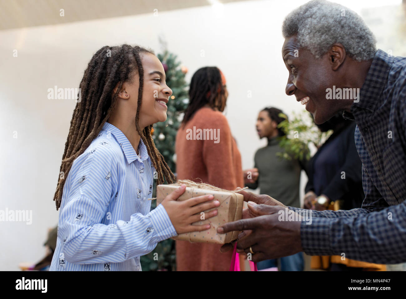 Happy grandfather giving Christmas gift to granddaughter Stock Photo