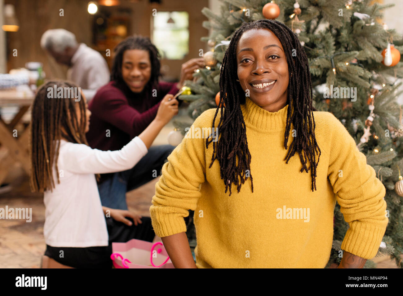 Portrait smiling woman decorating Christmas tree with family Stock Photo