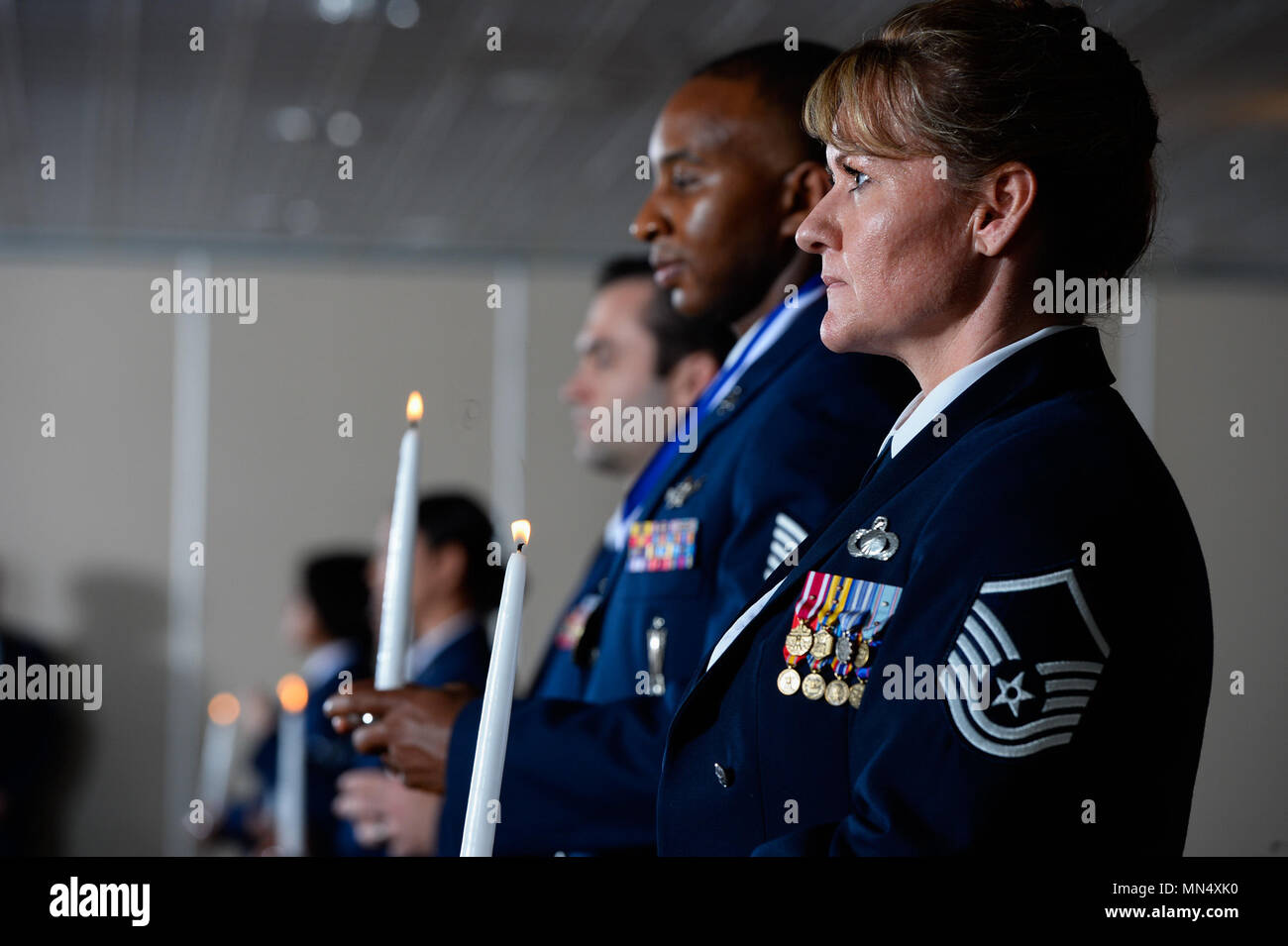 SCHRIEVER AIR FORCE BASE, Colo. -- Master Sgt. Kathy Blake, 50th Comptroller Squadron superintendent, stands alongside other Airmen in a candlelit procession during the Schriever Senior NCO Induction Ceremony at Peterson Air Force Base, Colorado, Friday, Aug. 11, 2017. The ranks of the Airmen in procession ascended from left to right, each symbolizing the roles of the inductees ranks to date. (U.S. Air Force photo/Chris DeWitt) Stock Photo