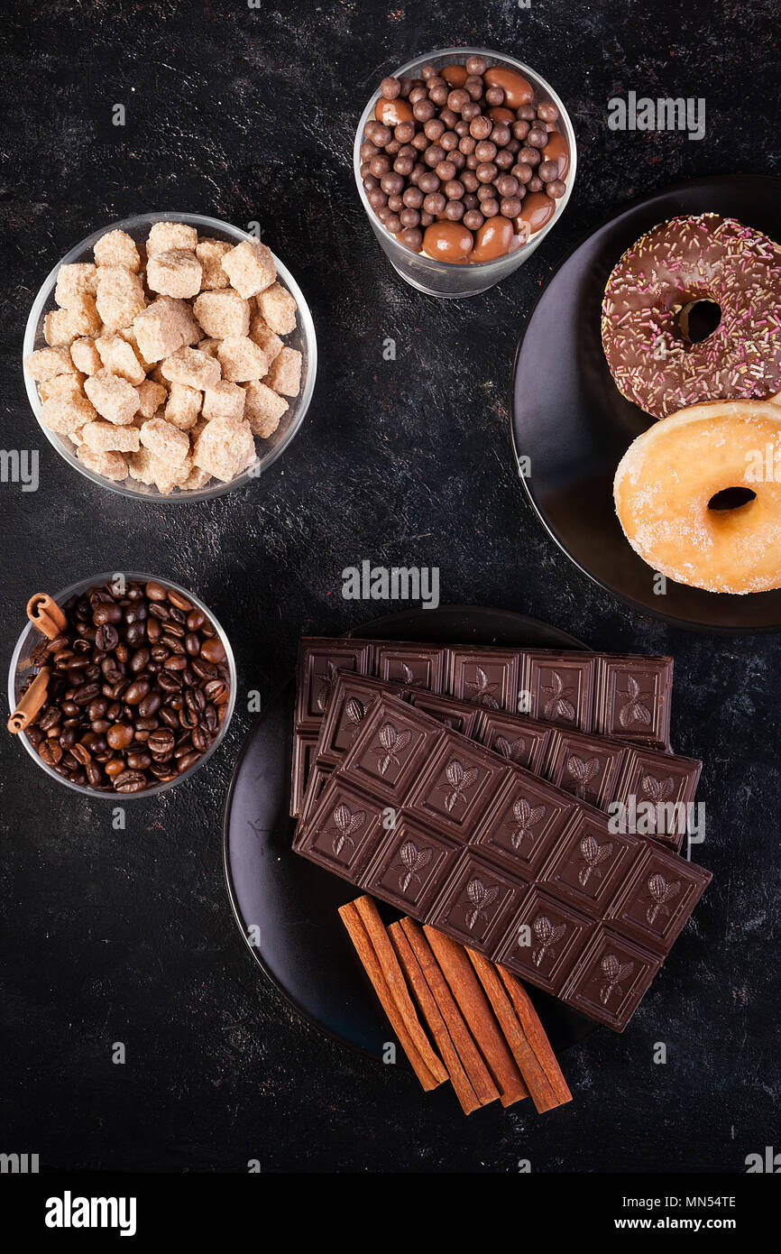 Top view of chocolate tablets, donuts, brown sugar with peanuts in
