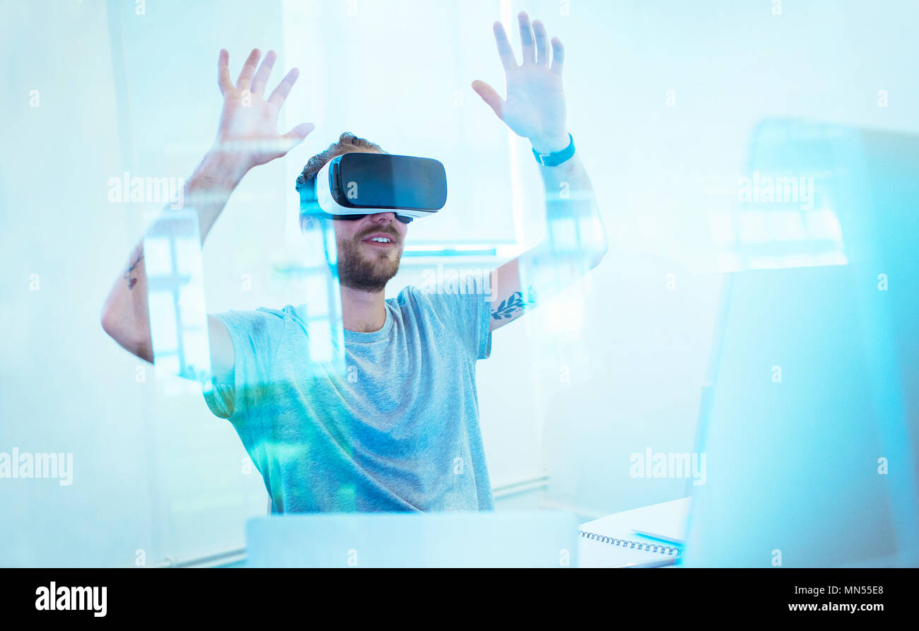 Male computer programmer testing virtual reality simulator glasses in office Stock Photo
