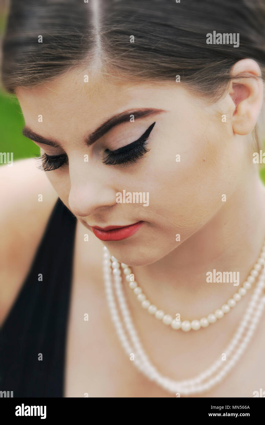 young caucasian woman looking down, closed eyes,pearl necklace Stock Photo