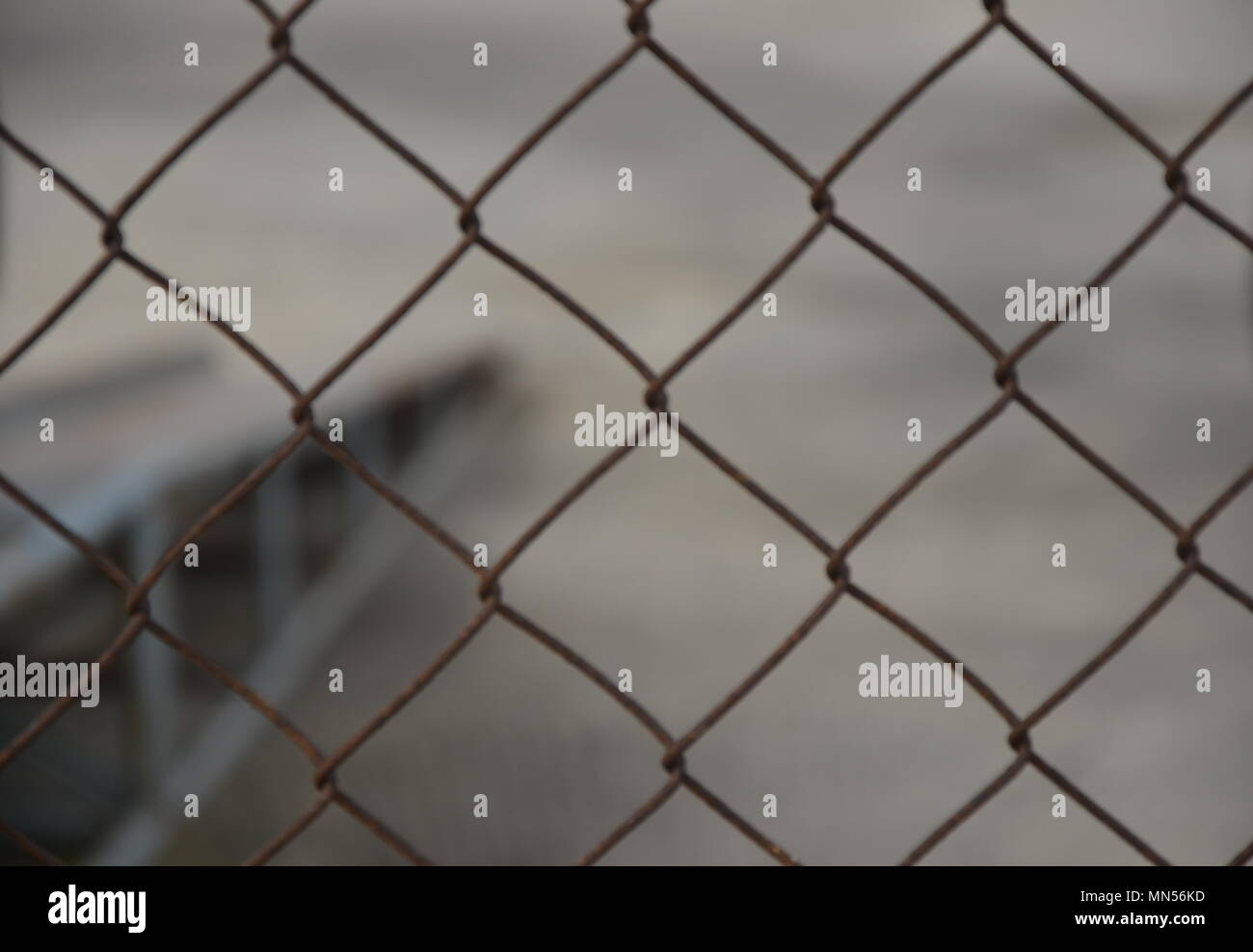 Chain link fence in front of gray unclear background Stock Photo