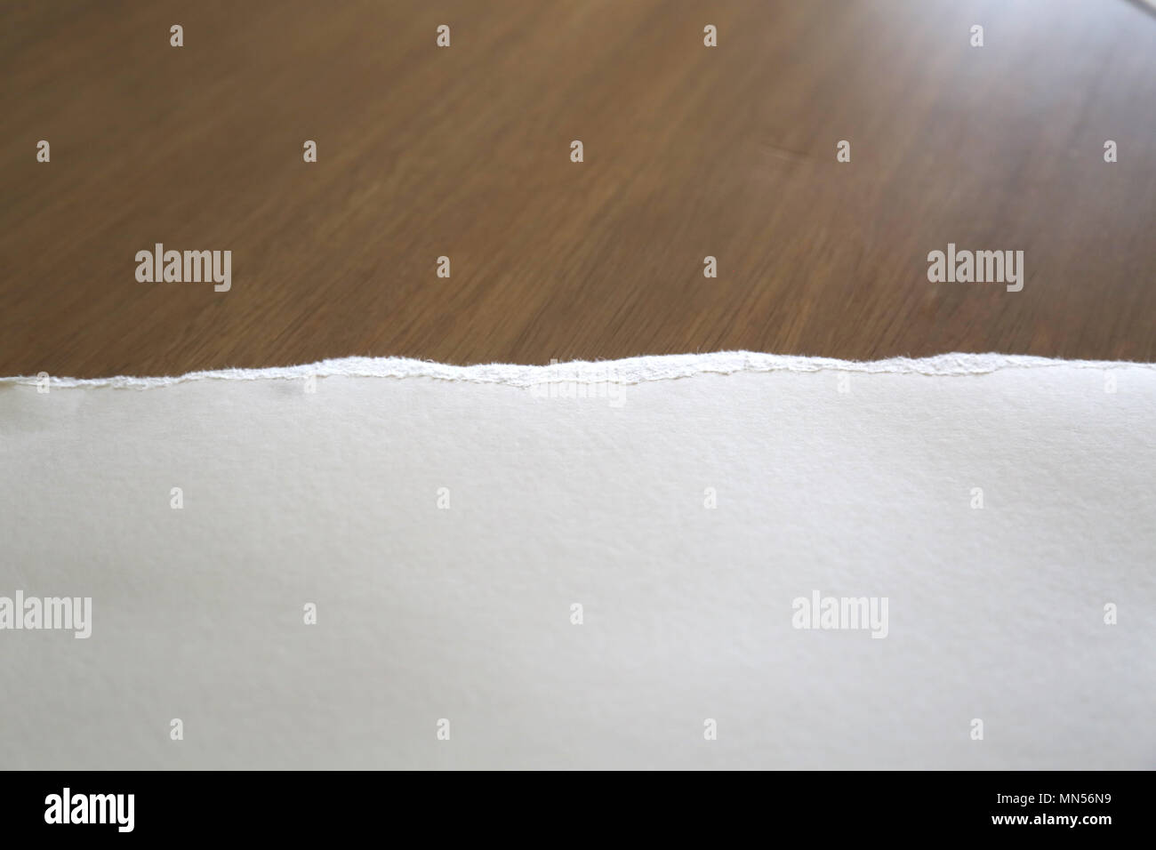 Torn white Paper on Brown Table Stock Photo