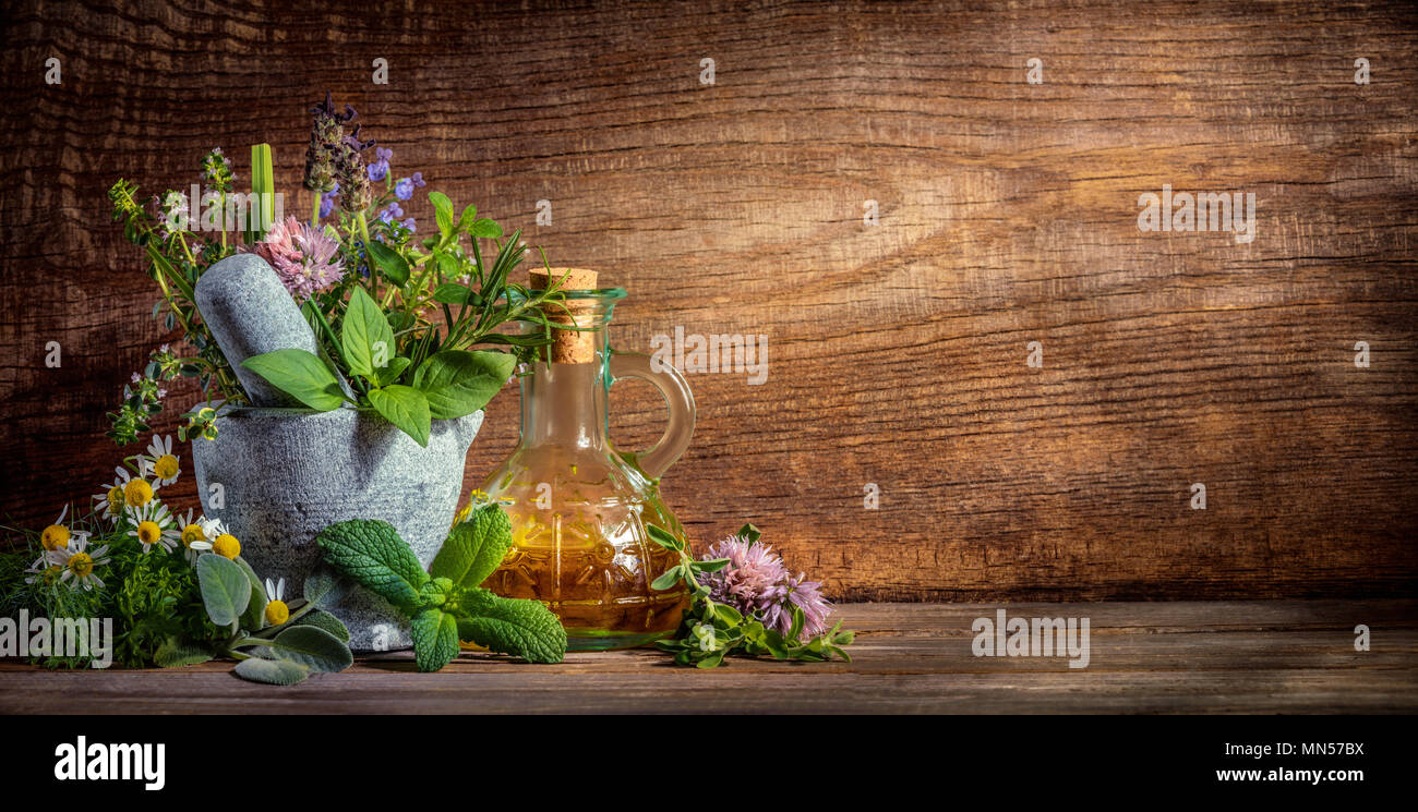 herbs,stone mortar and oil bottle on wooden background Stock Photo