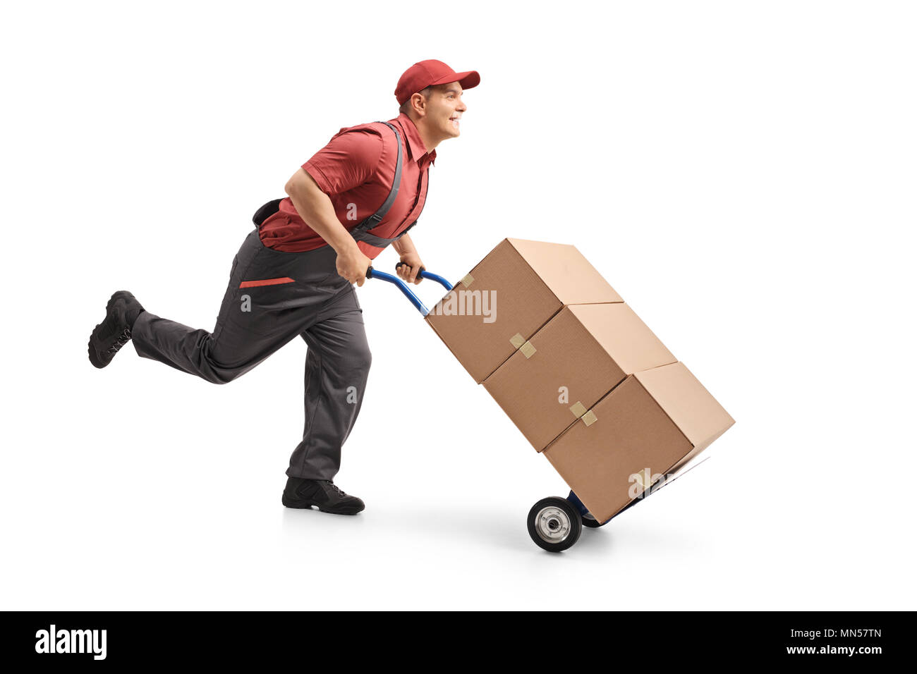 Full length profile shot of a mover running and pushing a hand truck loaded with boxes isolated on white background Stock Photo