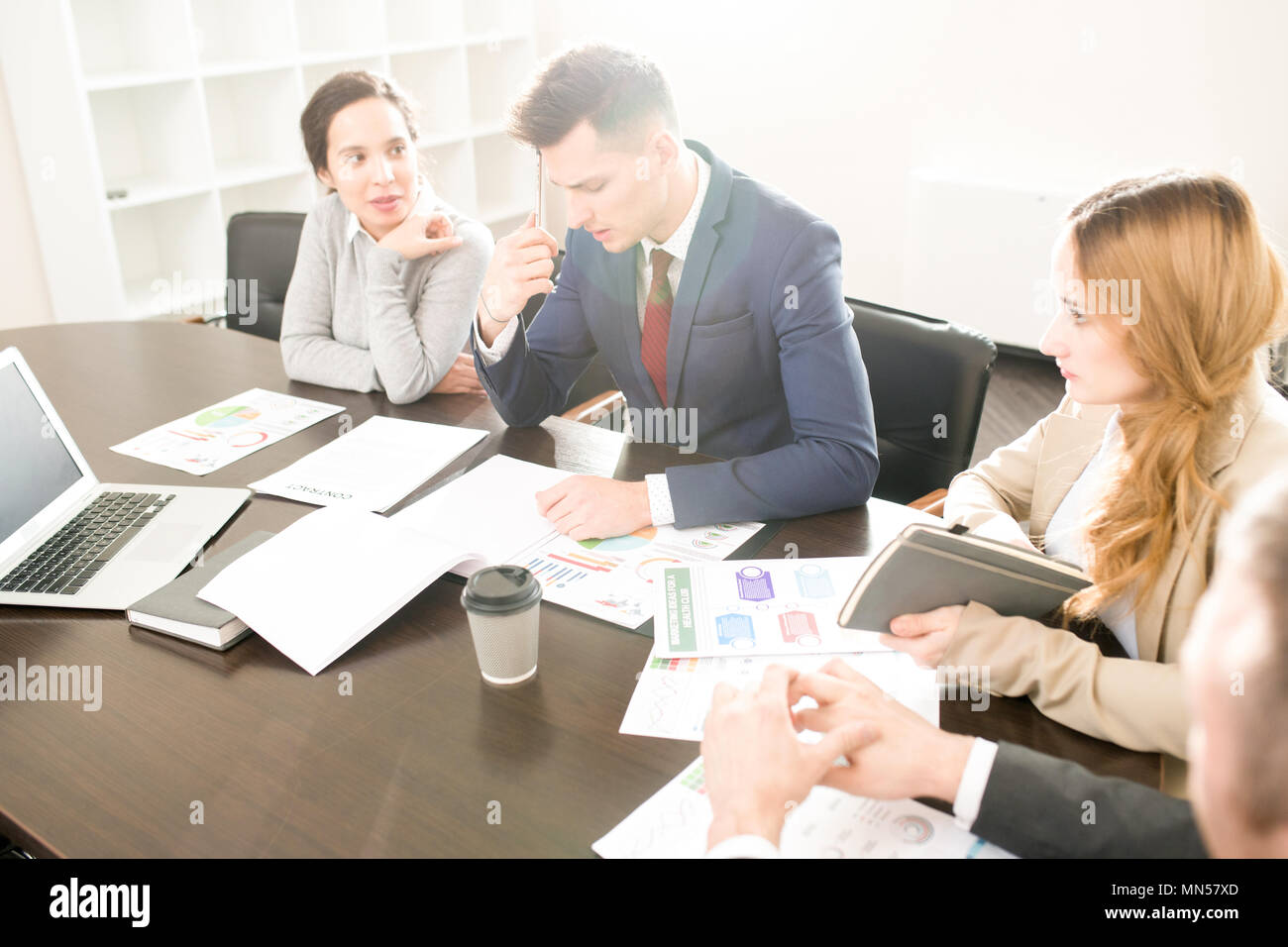 Portrait of four business people sitting at meeting table in conference ...