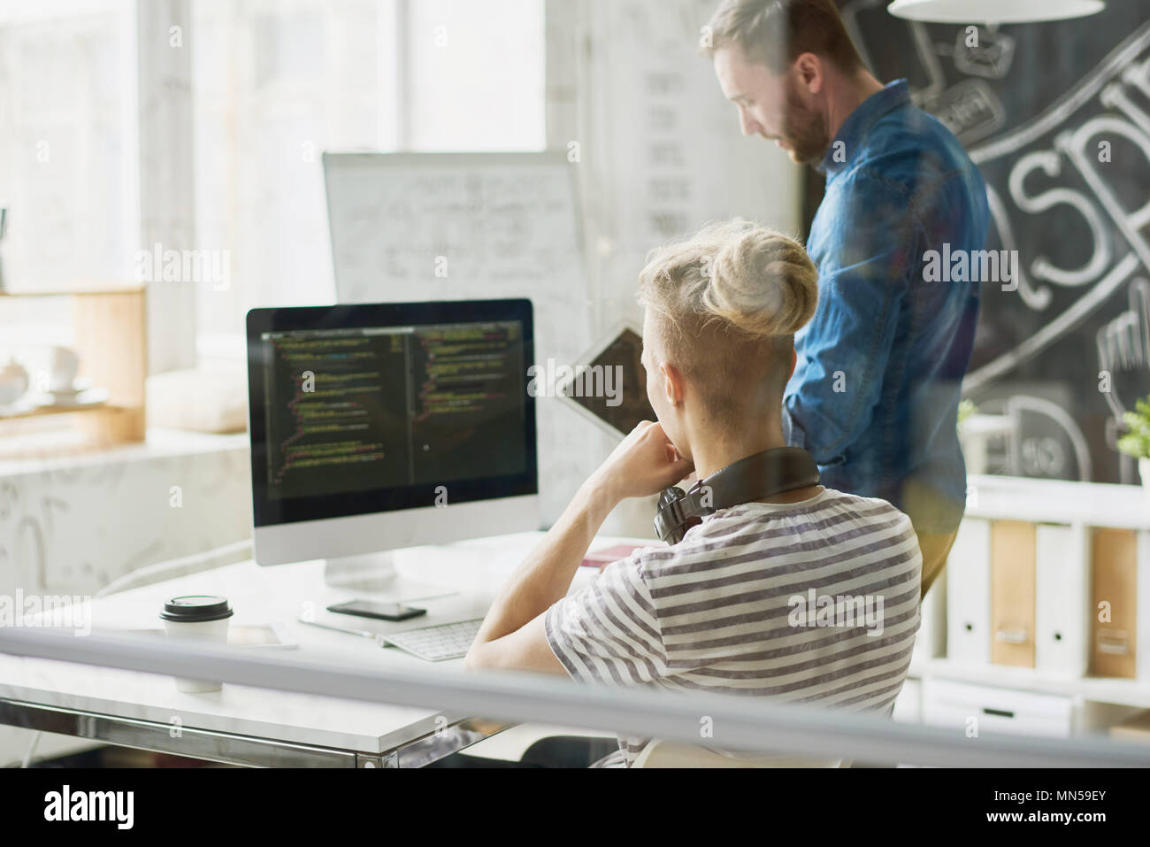 Back view portrait of two contemporary young men in casual wear coding ...