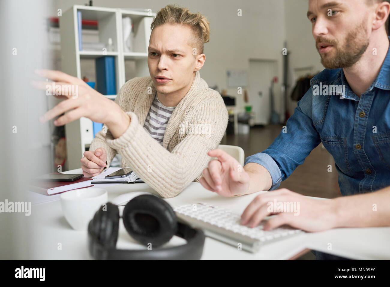 Portrait of two contemporary program developers writing code sitting at desk using computer and collaborating on startup project in modern office, cop Stock Photo
