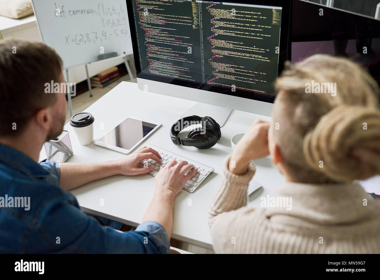 High angle view portrait of two contemporary program developers writing code sitting at desk using computer and collaborating on startup project in mo Stock Photo