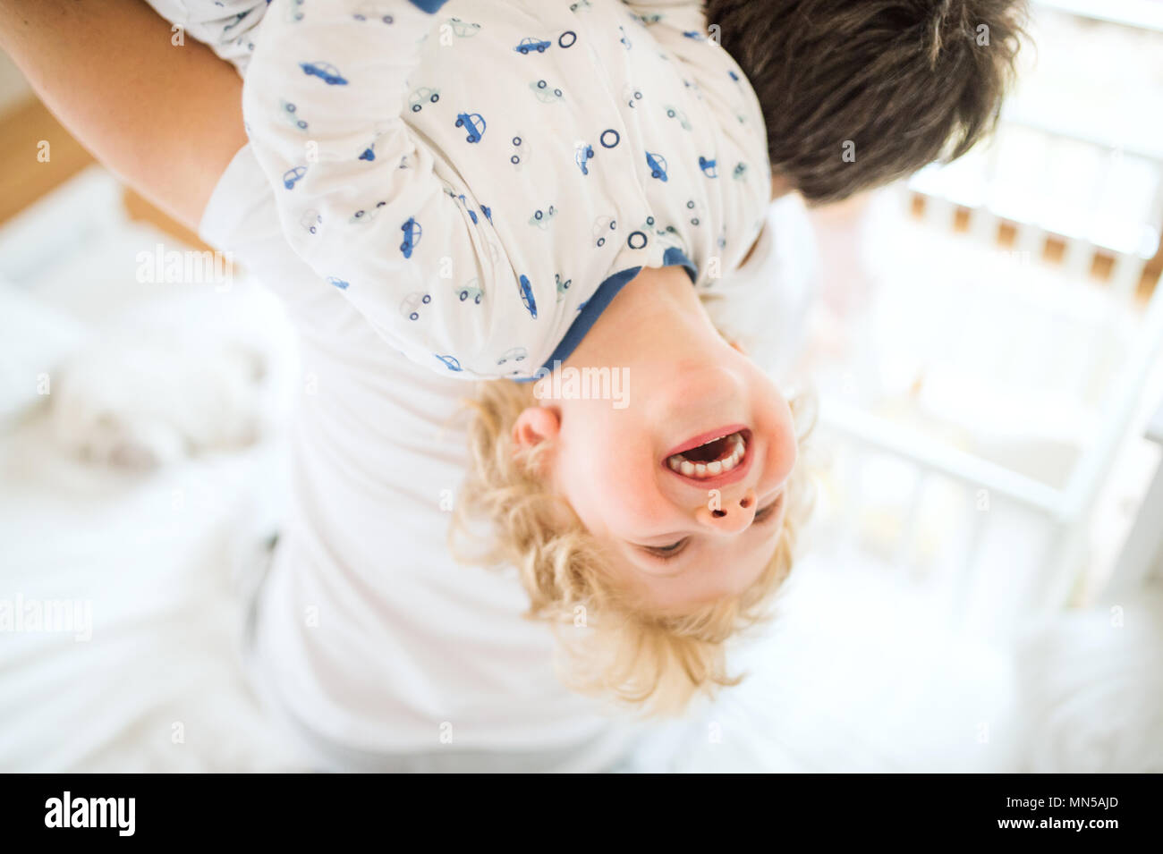 Unrecognizable father holding a happy toddler boy upside down. Paternity leave. Stock Photo