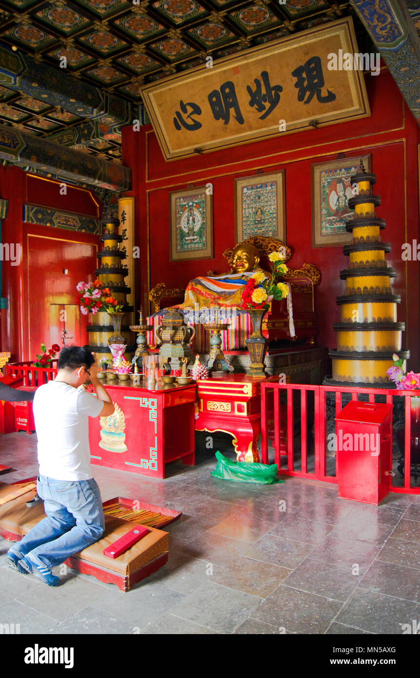 Chinese man praying at a shrine at the historic Yonghegong Temple in
