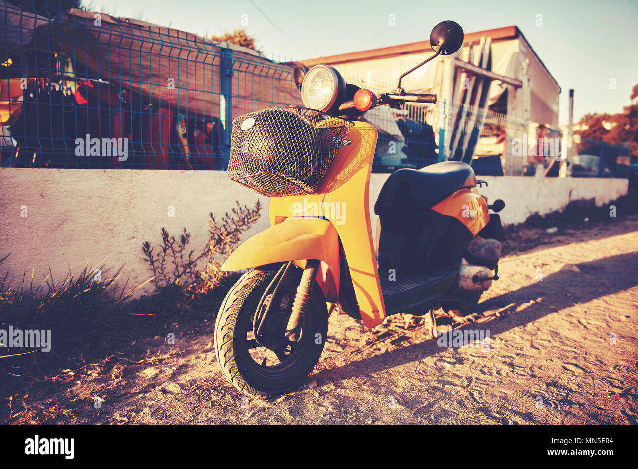 Yellow scooter parked on a soil road in a sunny afternoon Stock Photo