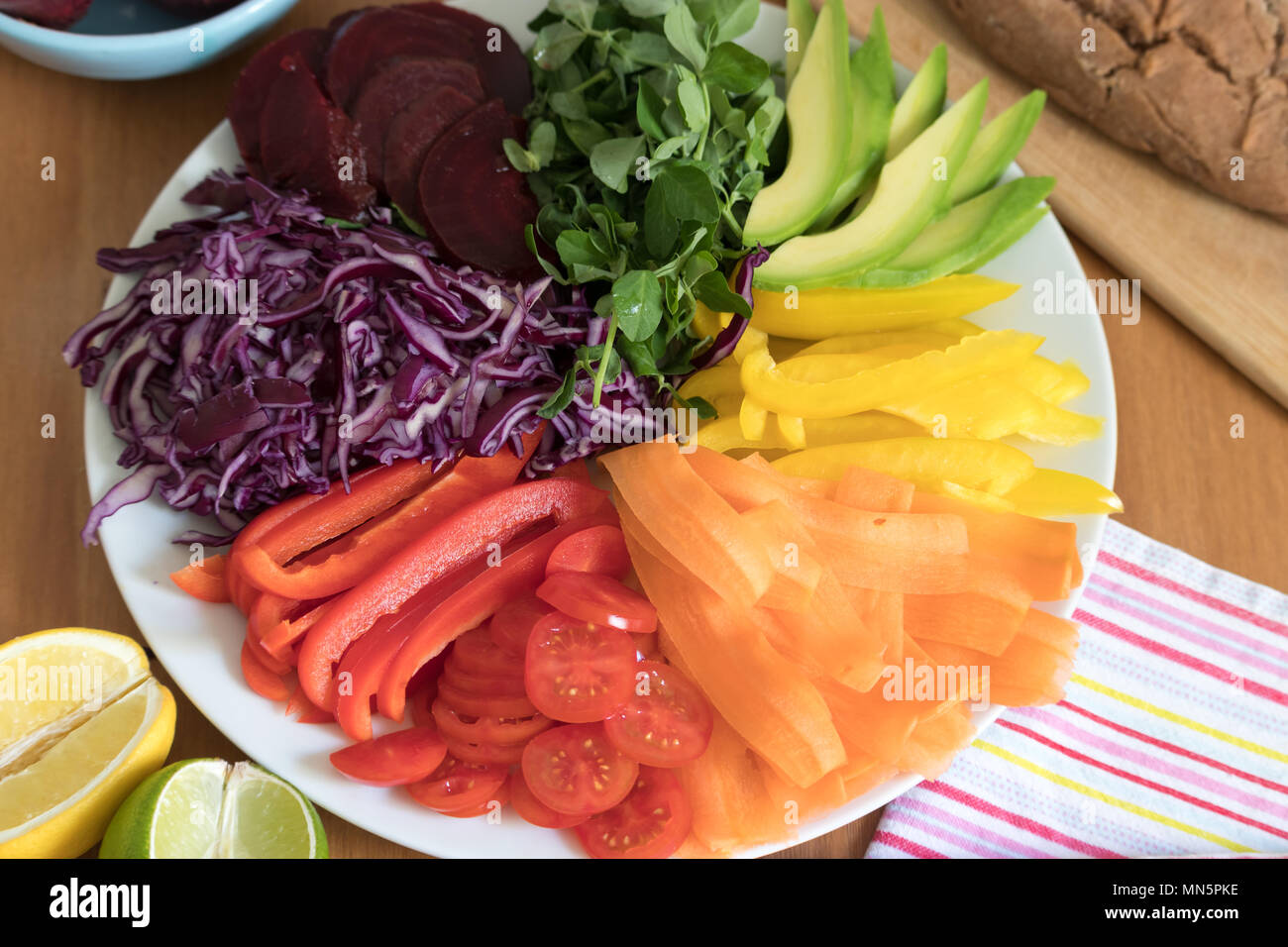 Rainbow salad with fresh baked, gluten free buckwheat bread. This healthy meal includes avocado, peppers, carrot tomato, beetroot, cabbage & peashoots. Stock Photo