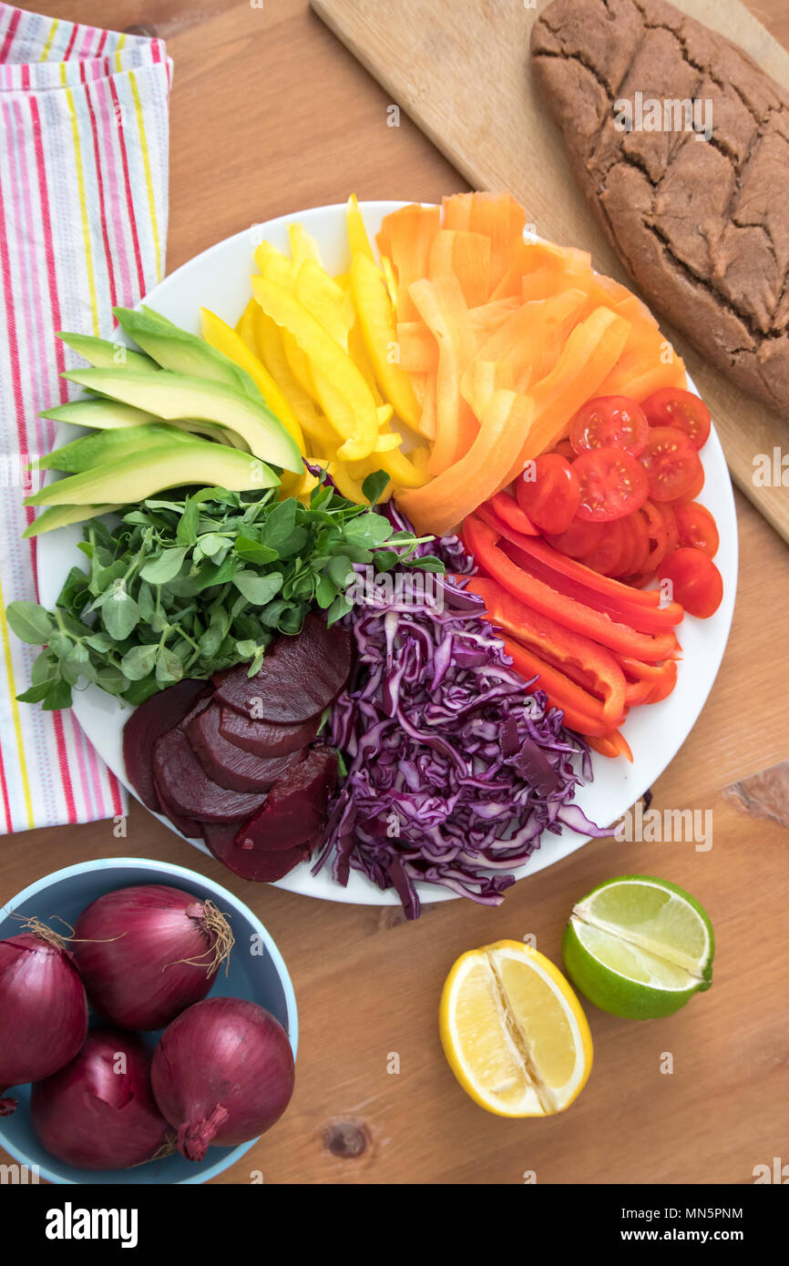 Rainbow salad with fresh baked, gluten free buckwheat bread. This healthy meal includes avocado, peppers, carrot tomato, beetroot, cabbage & peashoots. Stock Photo
