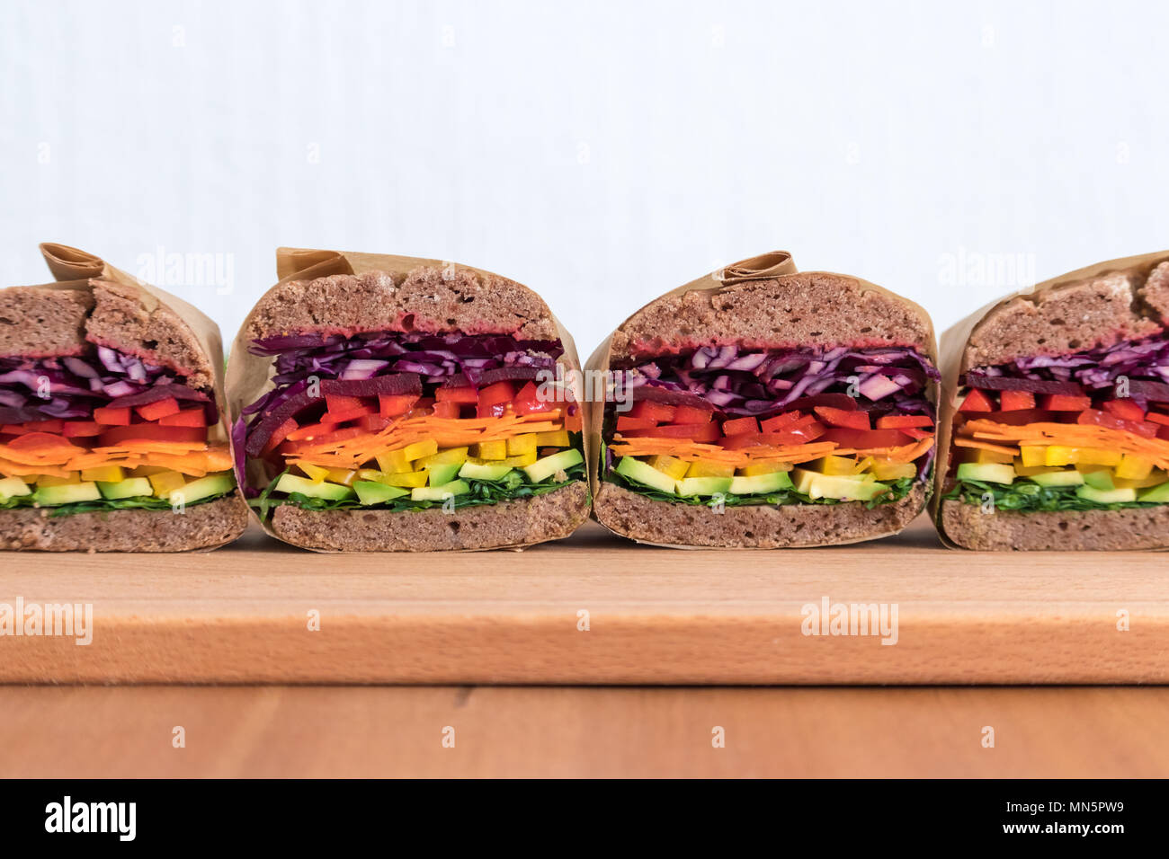 Rainbow salad sandwiches with homemade buckwheat bread, displayed on a wooden board. This fresh healthy lunch is low calorie, dairy free & gluten free. Stock Photo