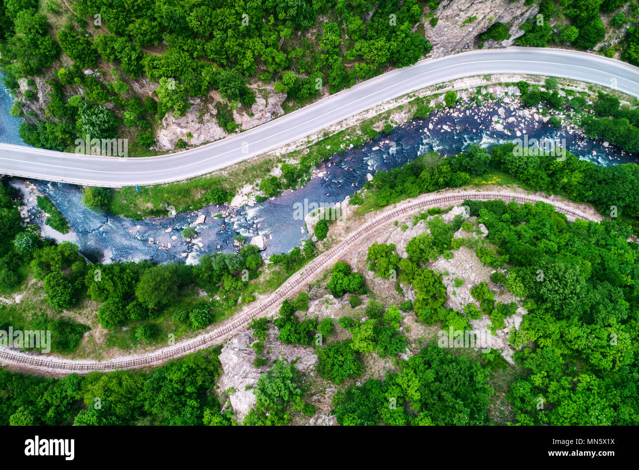 Aerial view of drone over mountain road and curves going through forest landscape Stock Photo